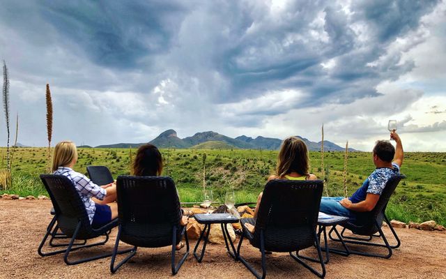 Guests with a glass of wine looking out over the Sonoita grasslands at Rune Wines